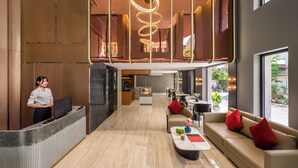 A modern hotel lobby with a reception desk, seating area, and large windows. - Xhome Da Nang Hotel and Suite  (Da Nang)
