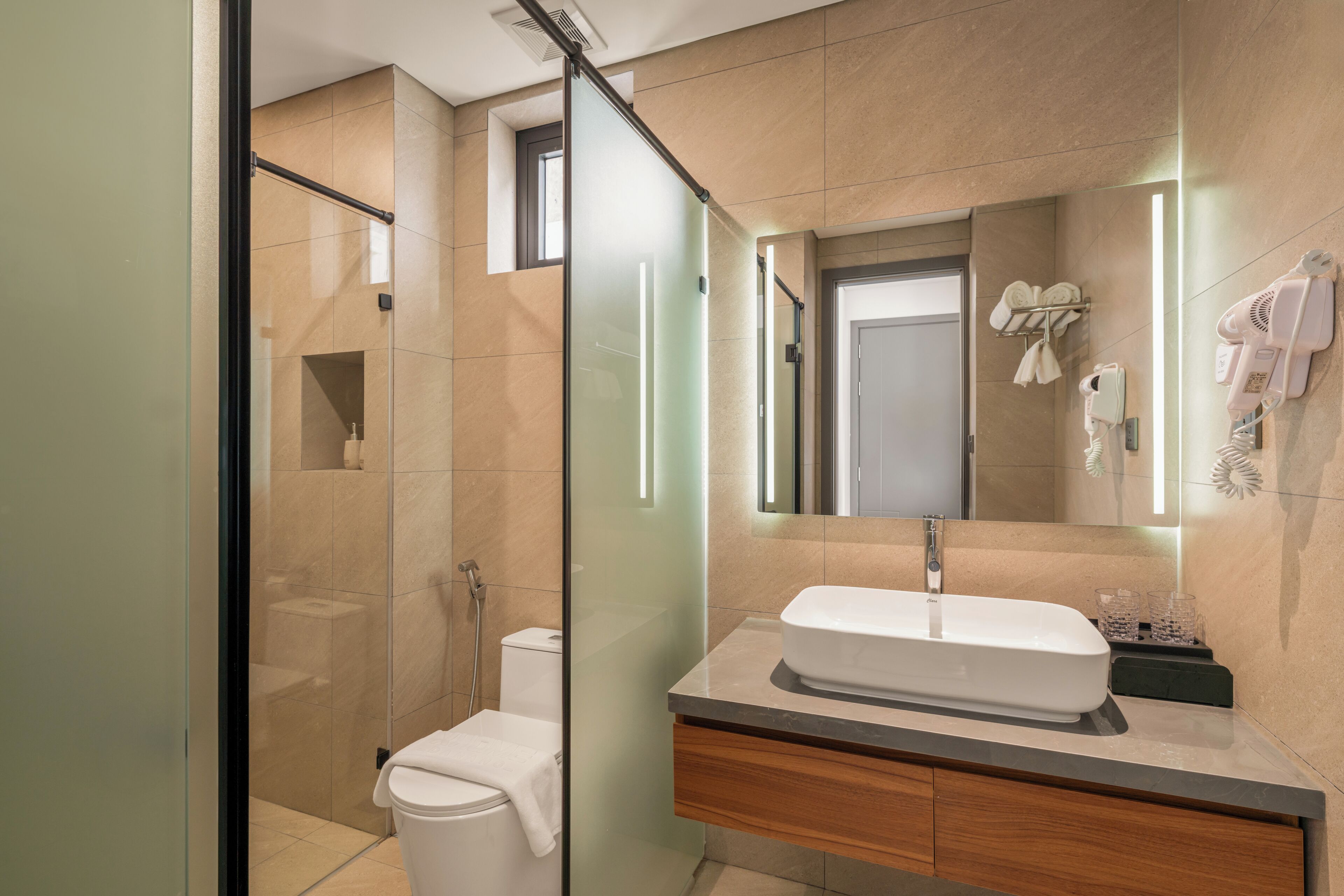 A modern bathroom with a glass shower enclosure, a white sink, and a vanity with a mirror.