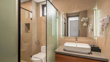 A modern bathroom with a glass shower enclosure, a white sink, and a vanity with a mirror.