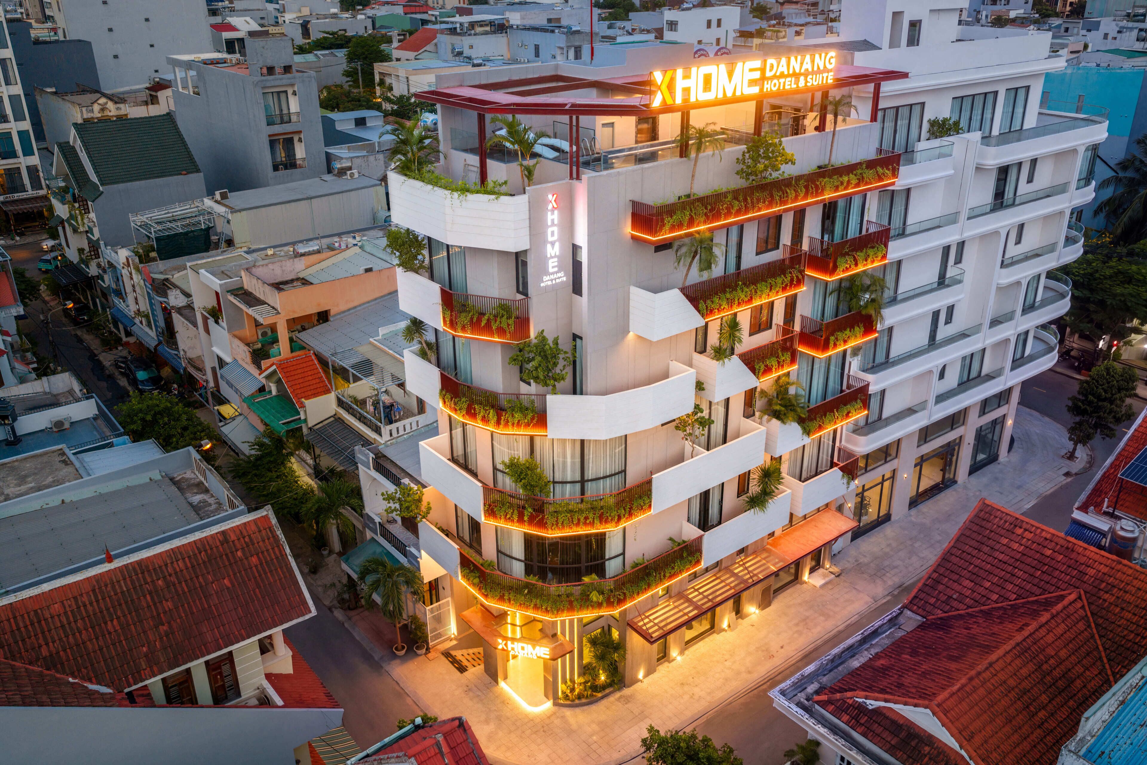 A multi-story hotel with balconies, a rooftop terrace, and a sign reading 'XHOME DANAING HOTEL & SUITE'.