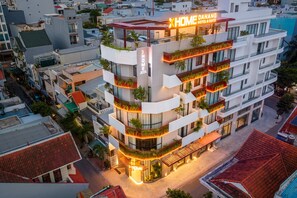 Un hotel de varios pisos con balcones, una terraza en la azotea y un cartel que dice 'XHOME DANAING HOTEL & SUITE'.