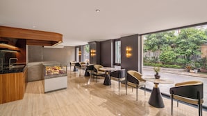 A modern interior with a kitchen, seating area, and large windows with a view of greenery. - Xhome Da Nang Hotel and Suite  (Da Nang)
