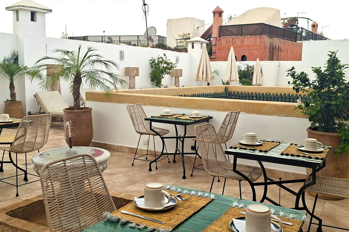 A rooftop terrace with outdoor seating, potted plants, and a view of the cityscape.