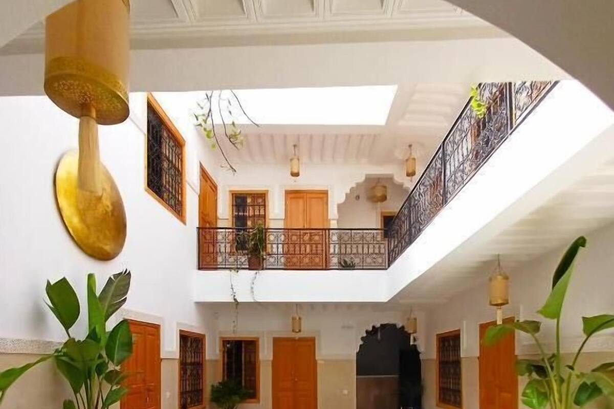 A swimming pool with a tiled border, a balcony with a railing, and potted plants.