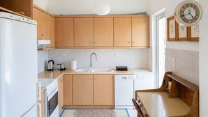 A compact kitchen with wooden cabinets, a white sink, a white dishwasher, and a white stove.