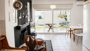 A modern living room with a fireplace, a dining area with a table and chairs, and a view of the outside.