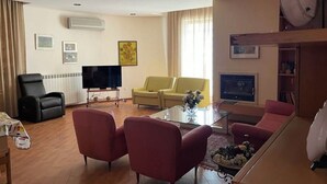 Un soggiorno con televisione, divano, poltrone e tavolino.