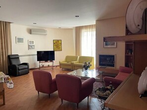 Un salon comprenant un téléviseur, un canapé, des fauteuils et une table basse.