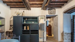 Una habitación con una cama, un armario oscuro con estantes, una lámpara de pie y una pared de piedra.