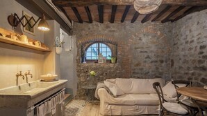 Una cocina rústica con paredes de piedra, techo de madera, un sofá blanco y una mesa de comedor.