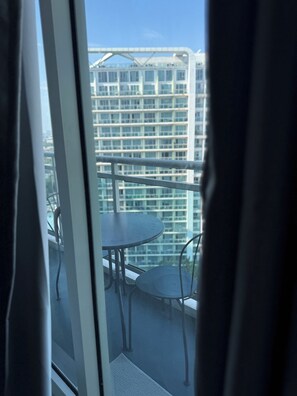 A balcony with a table and chairs, overlooking a high-rise building. - 2 Bedroom Unit with Beach View near Airport (Taguig)