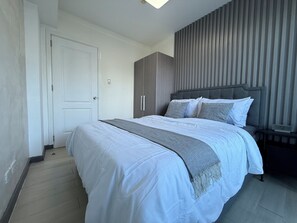A bedroom with a bed, a wardrobe, a nightstand, and a wall-mounted panel. - 2 Bedroom Unit with Beach View near Airport (Taguig)