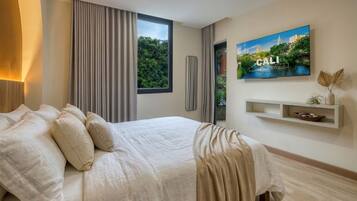 A modern bedroom with a large bed, a window with curtains, a wall-mounted TV, and a shelf with decorative items.