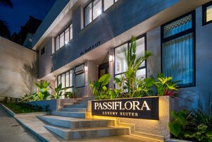 Un edificio moderno con un cartel que indica 'Passiflora Luxury Suites' en la entrada.