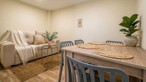 A cozy living room with a sofa, a small side table, a potted plant, and a dining area with a wooden table and chairs. - Passiflora luxury suite (Cali)