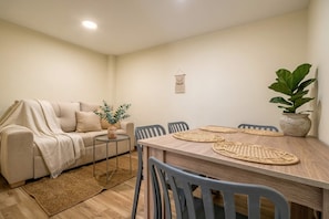 A cozy living room with a sofa, a small side table, a potted plant, and a dining area with a wooden table and chairs. - Passiflora luxury suite (Cali)