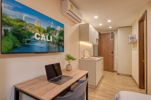 A modern hotel room with a laptop on a desk, a sink, a mirror, and a door with a number sign. - Passiflora luxury suite (Cali)