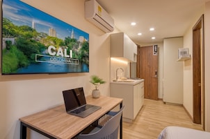 Une chambre d’hôtel moderne avec un ordinateur portable sur un bureau, un lavabo, un miroir et une porte portant un numéro.