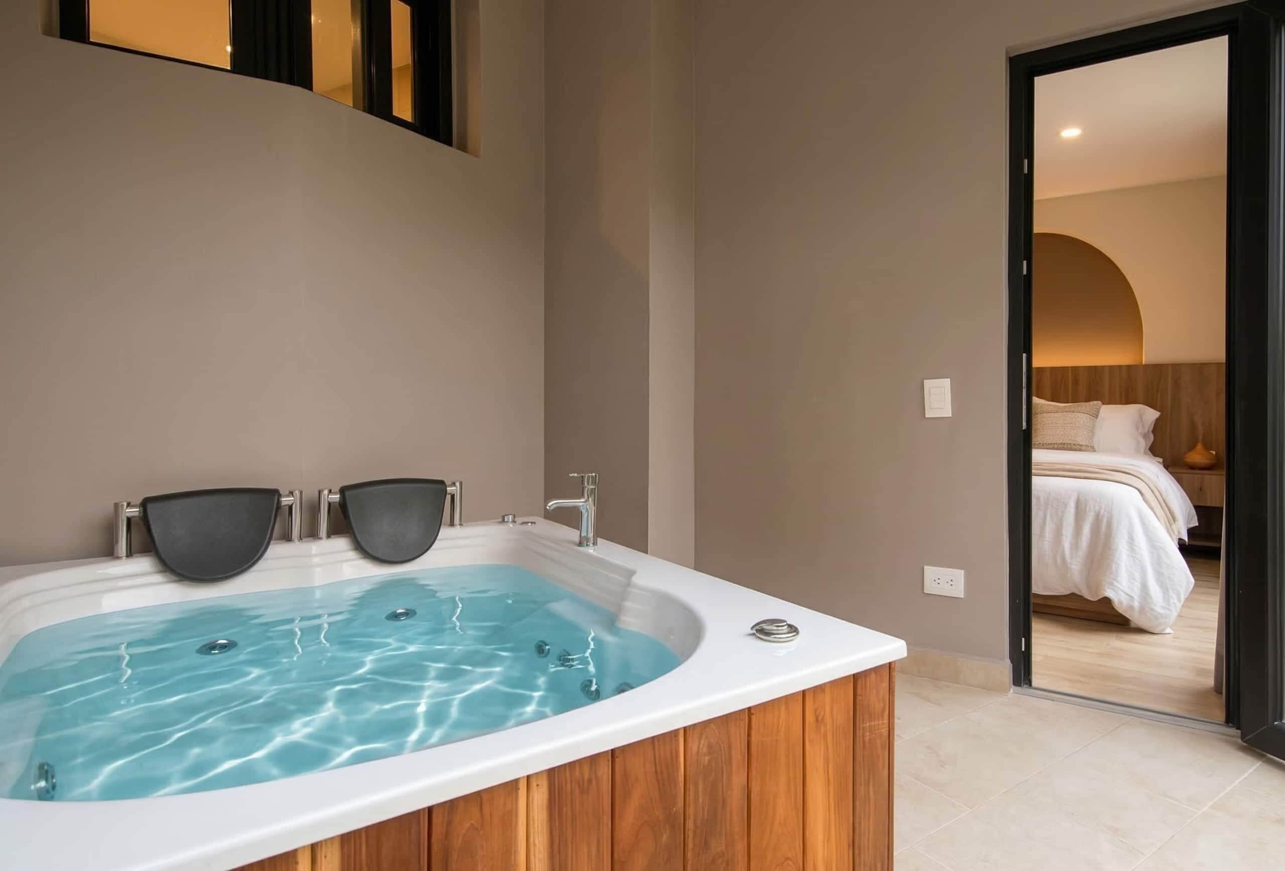 Une salle de bain moderne avec une baignoire sur pieds, un miroir et une porte donnant sur une chambre.