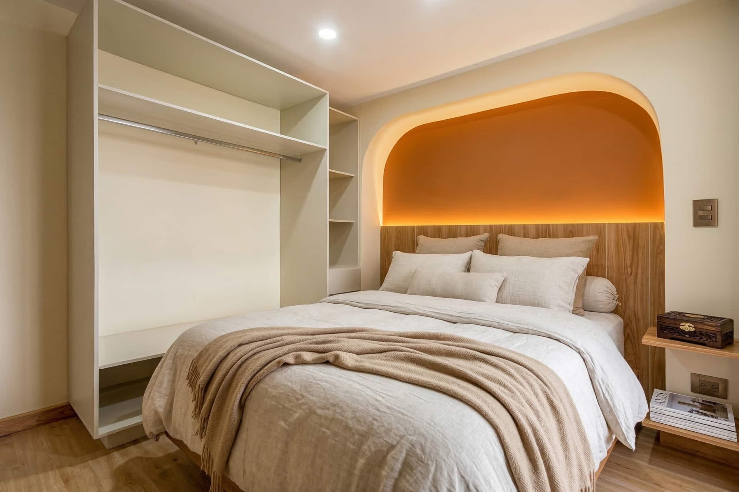 Een slaapkamer met een bed, een kledingkast en een nachtkastje met een lamp.