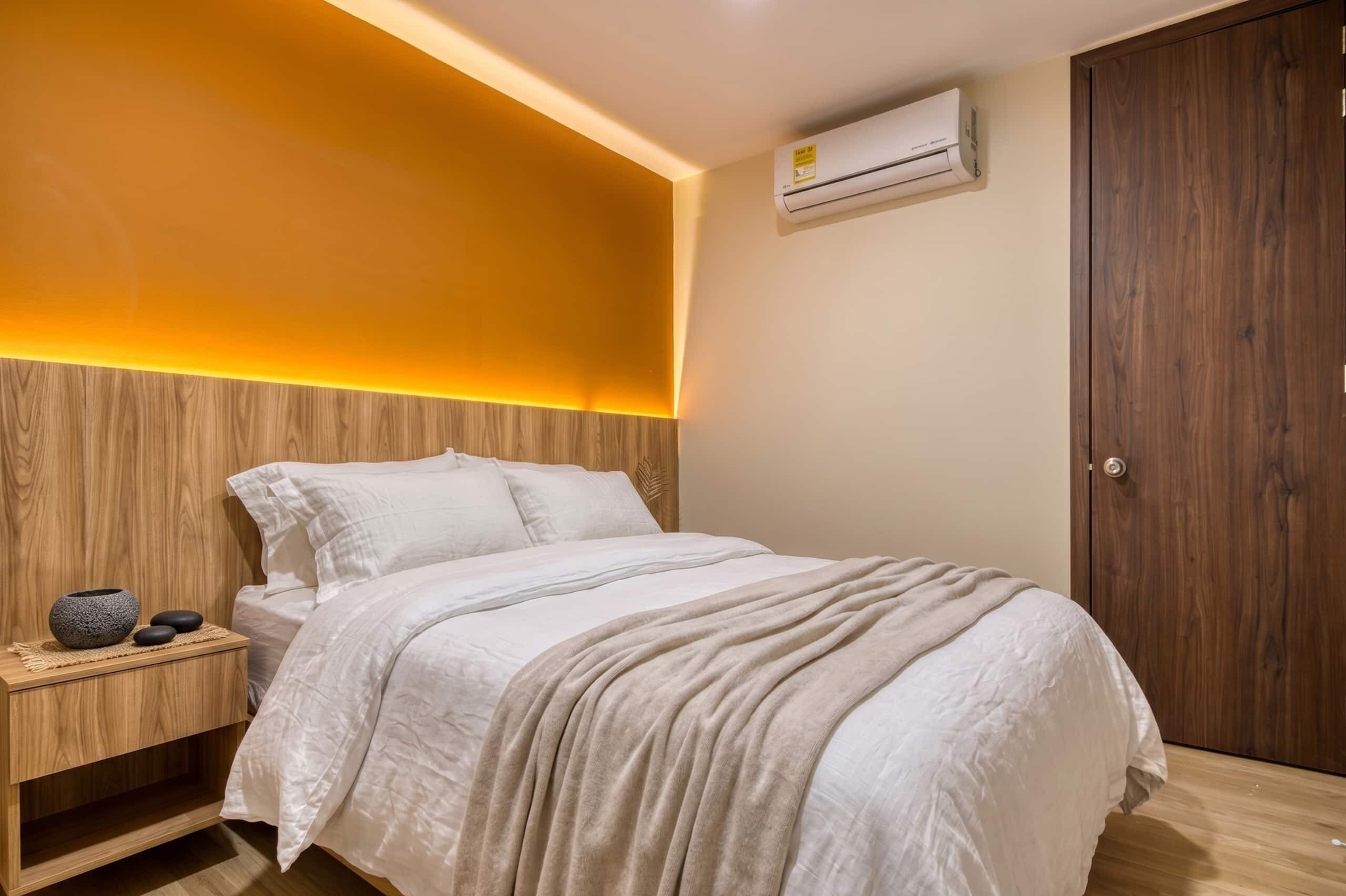 Un dormitorio con cama, mesita de noche y equipo de aire acondicionado.