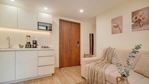 A modern kitchen with white cabinets, a wooden door, and a microwave above the counter. - Passiflora luxury suite (Cali)