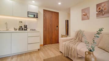 A modern kitchen with white cabinets, a wooden door, and a microwave above the counter.