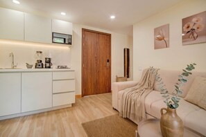 A modern kitchen with white cabinets, a wooden door, and a microwave above the counter. - Passiflora luxury suite (Cali)
