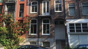 Un edificio residencial de varios pisos con fachada de ladrillo, múltiples ventanas y una puerta de garaje visible.
