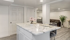 Una cocina moderna con armarios blancos, encimera de mármol y una isla central decorada con un arreglo floral.