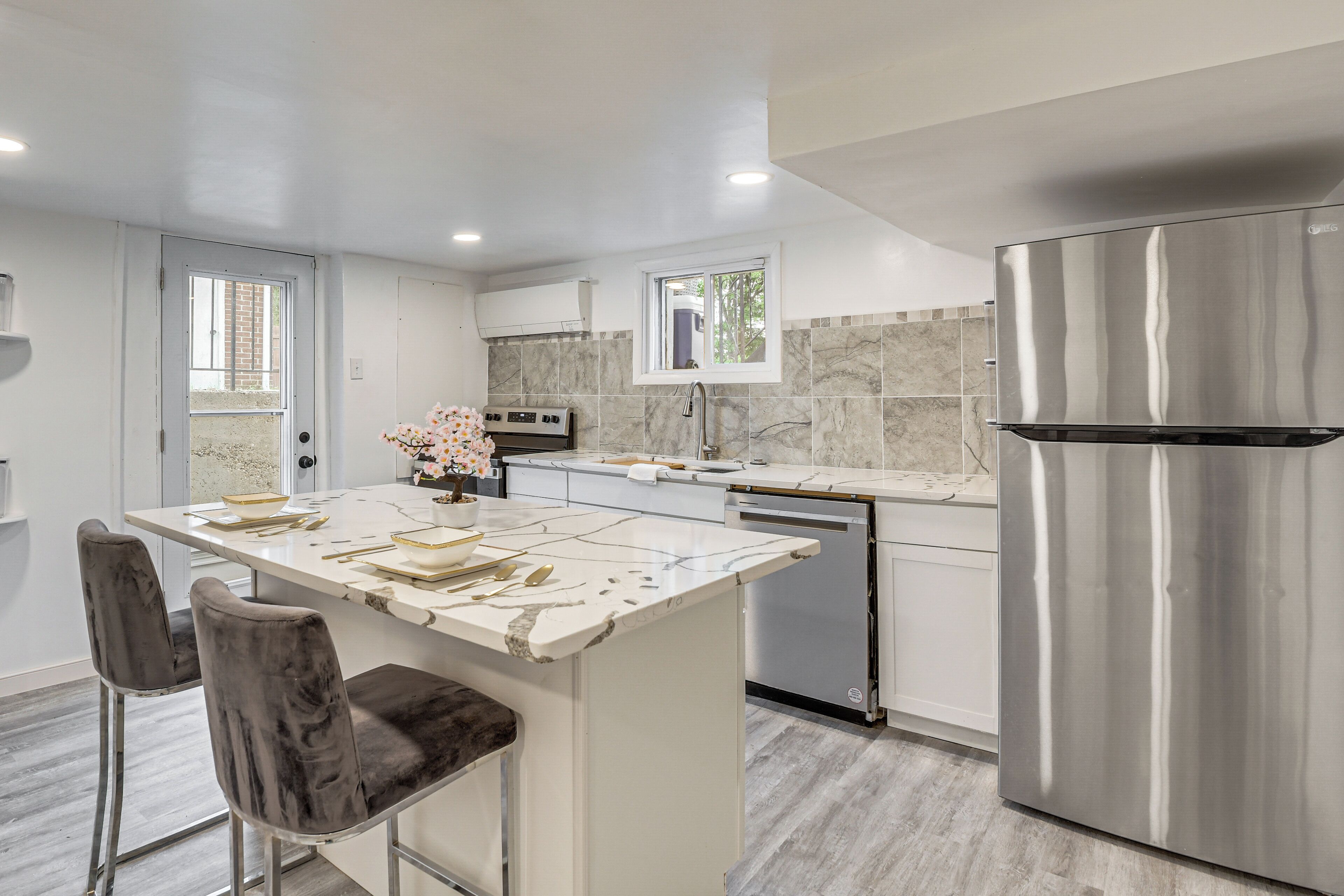 A modern kitchen with a marble countertop, stainless steel appliances, and a central island with bar stools.