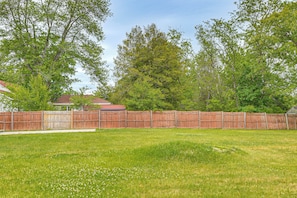A fenced backyard with a grassy lawn and trees.