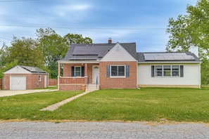 A two-story house with a brick facade, a garage, and a solar panel on the roof.