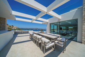 Eine moderne Außenpatio mit Essbereich, Steinmauern und Blick auf den Ozean.