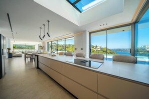 Eine moderne Küche mit einer großen Kochinsel, großen Fenstern und Blick auf die Landschaft.