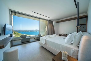 Ein modernes Hotelzimmer mit einem großen Bett, einem Fernseher, einem Schreibtisch und Meerblick.