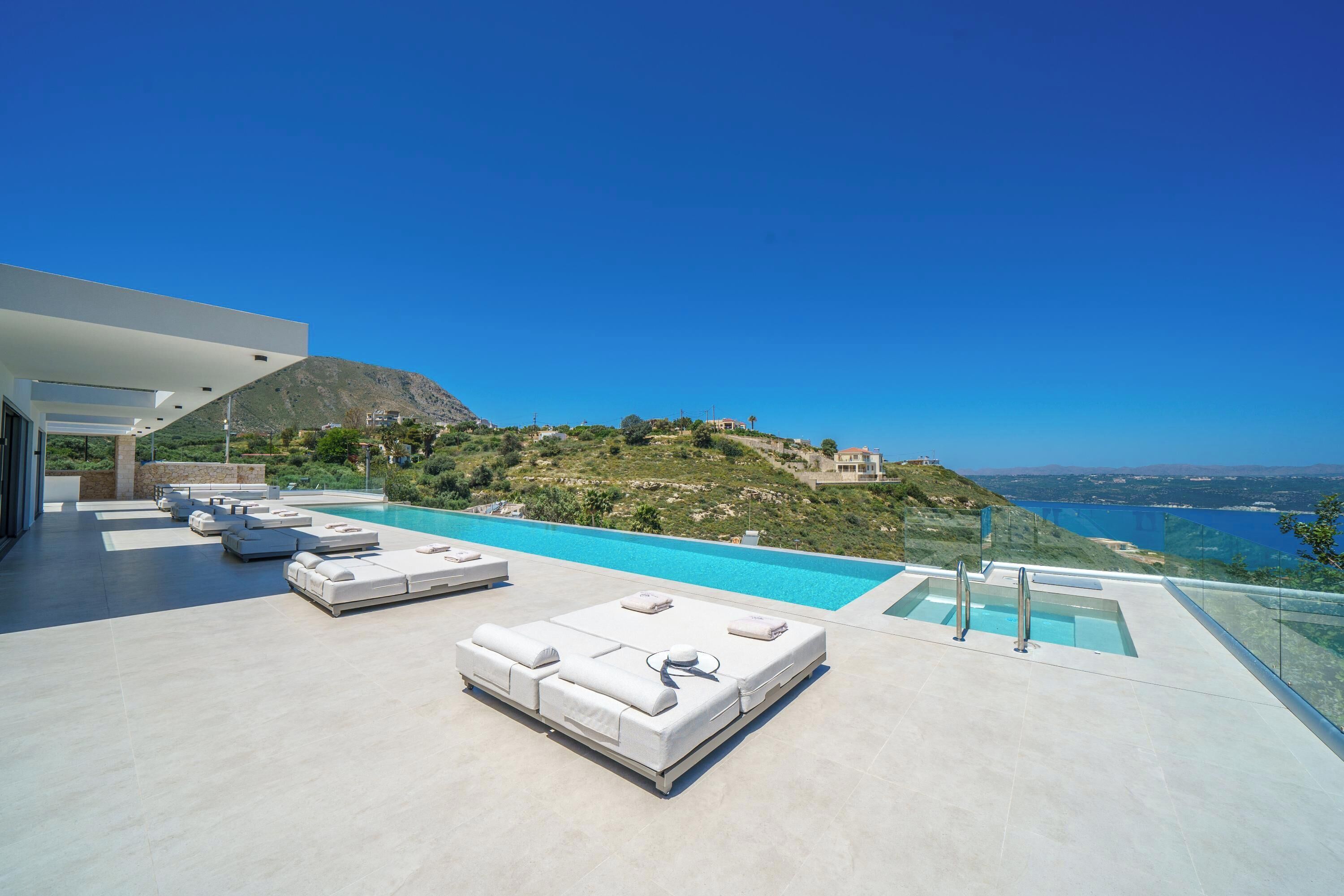 Un espace piscine extérieur moderne, doté de chaises longues et offrant une vue dégagée sur le paysage environnant.
