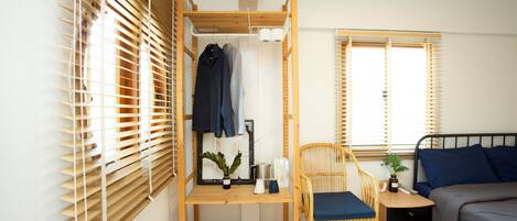 A room with a bunk bed, a chair, a bedside table, and a wardrobe.