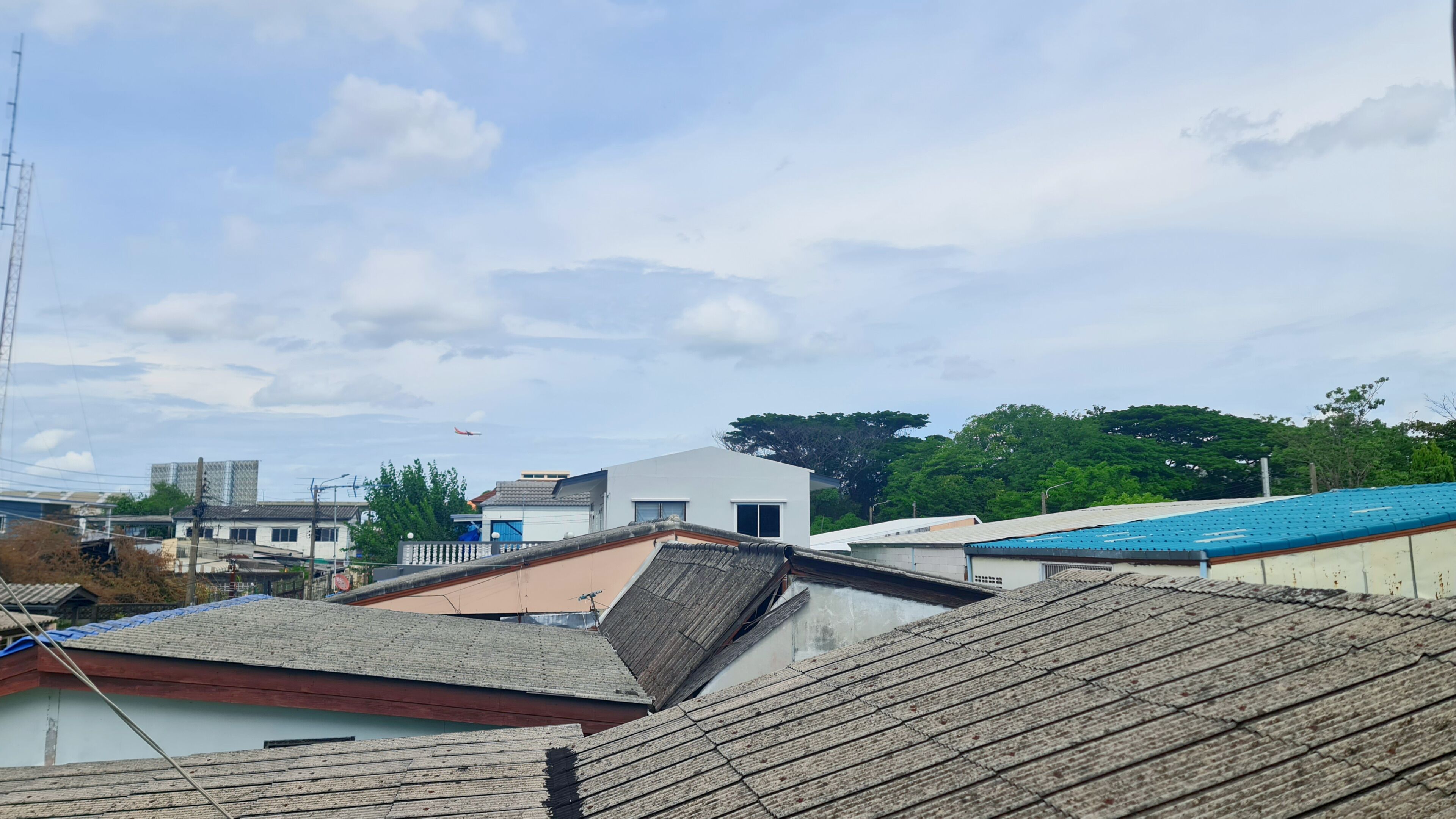 A residential area with various buildings, including a modern house with a flat roof and a traditional house with a sloped roof.