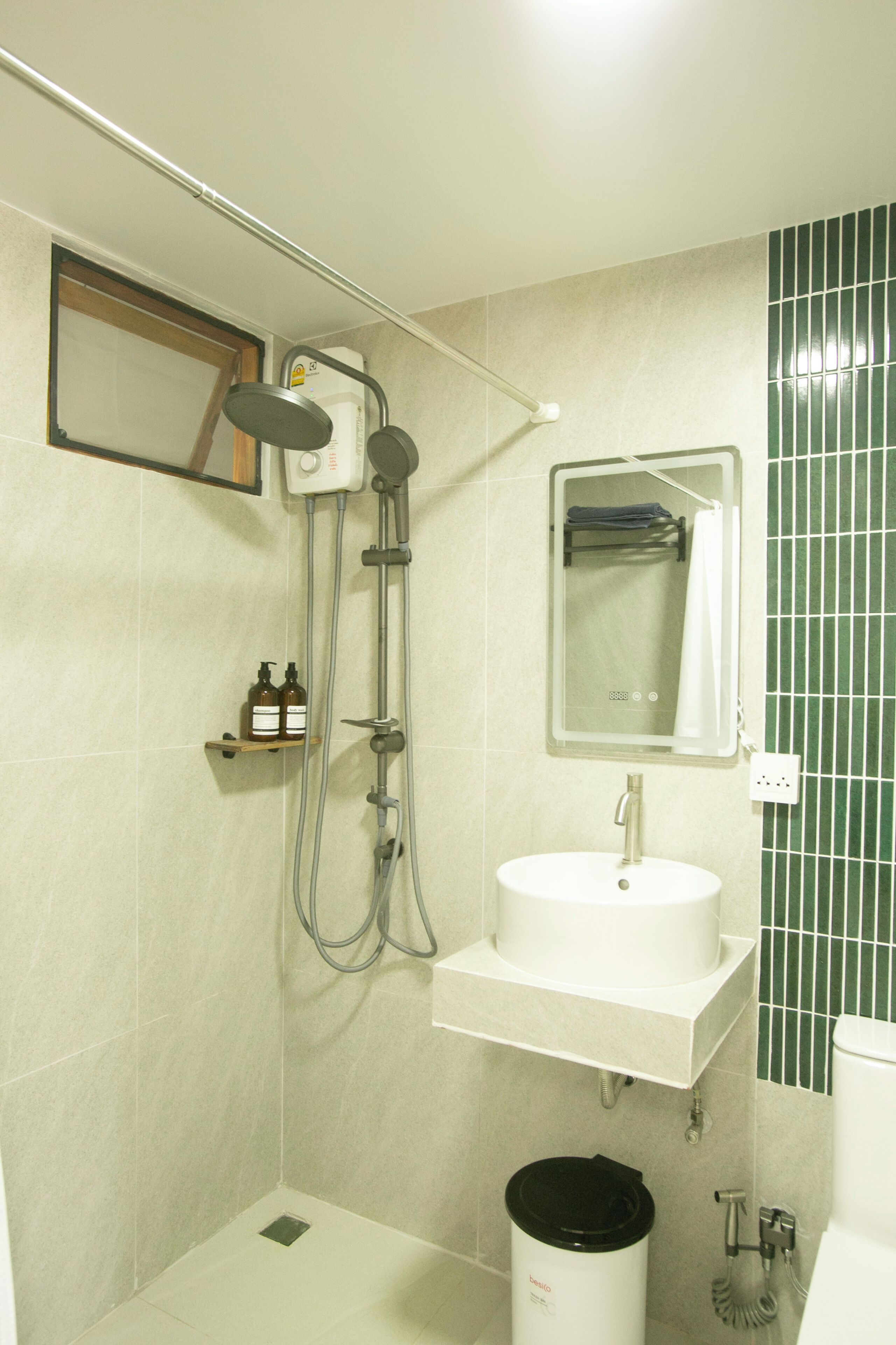 Ein Badezimmer mit Dusche, Waschbecken, Spiegel und Wand in Grün.