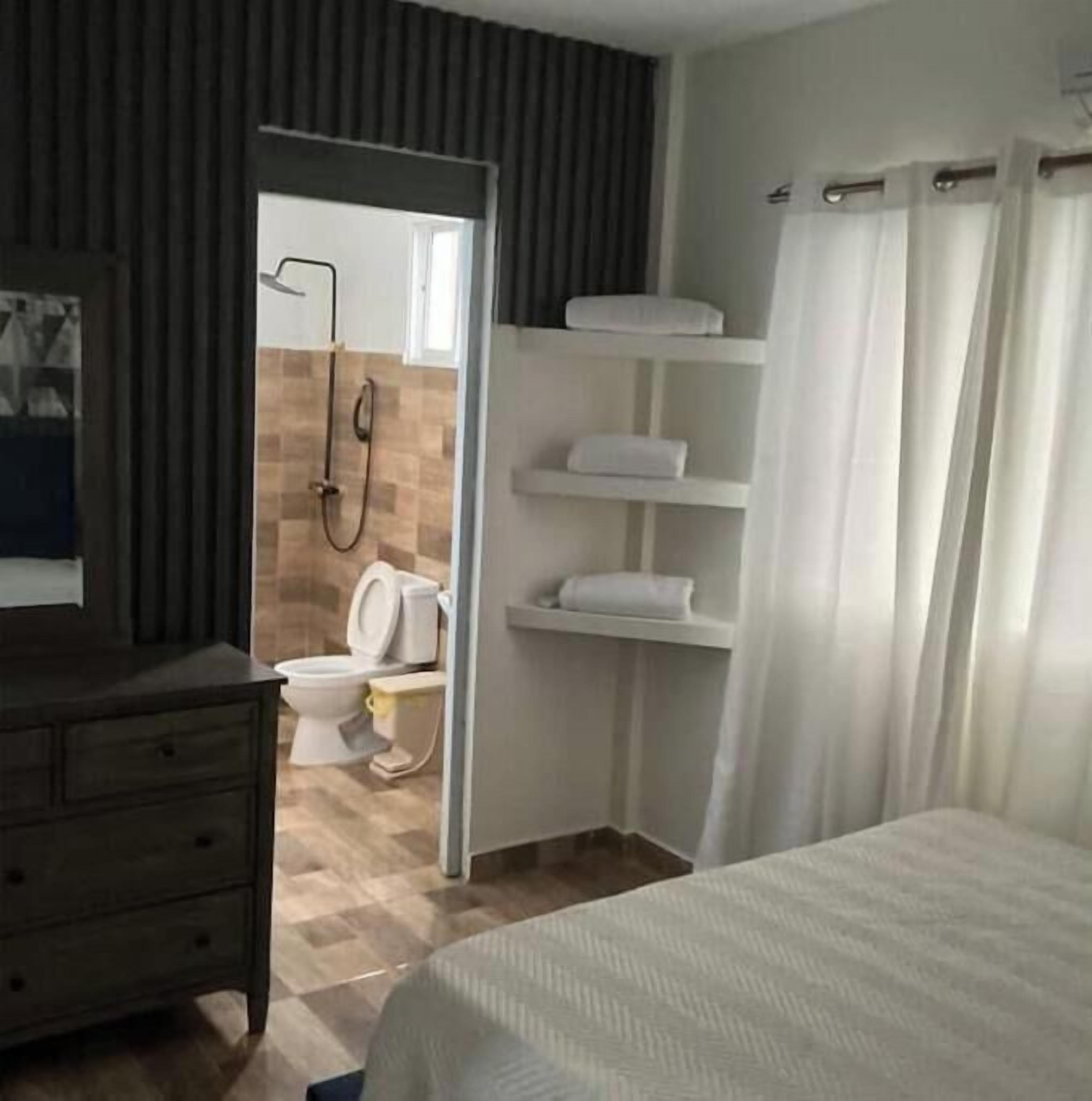 Ett hotellrum med en säng, en byrå, en dusch och en toalett.