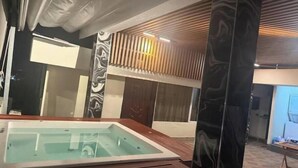 A modern room with a glass-enclosed hot tub, wooden paneling, and a view of the cityscape. - Apt Aconchegante+Private Jacuzzi+Wi-Fi+AC in Santo Domingo RD (Santo Domingo)