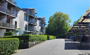 A residential street with multi-story buildings, a clear sky, and a parking area with cars. - Apartment Sonnenherz with balcony, WLAN and private parking space - Residential complex "Am (Wittenbeck)