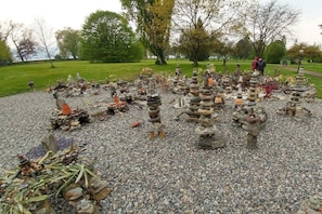 A garden with stone stacks and pebbles, surrounded by trees and a pathway. - Holiday apartment with 1 bedroom (Radolfzell)