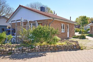 Une maison en briques avec un patio couvert, un mur en pierre et un ciel dégagé.