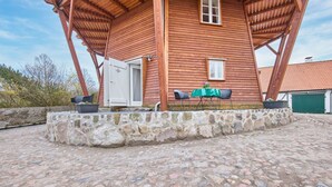 Una casa de madera con base de piedra, una puerta y una pequeña mesa con sillas afuera.