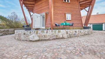 Ein Holzhaus mit Steinunterbau, einer Tür und einem kleinen Tisch mit Stühlen vor der Tür.