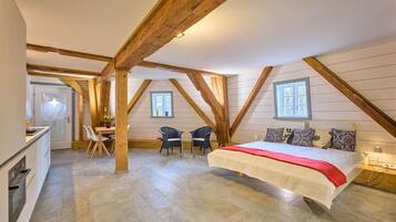 Ein Schlafzimmer mit einem großen Bett, Holzbalken, einem Schreibtisch und zwei Stühlen.