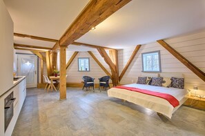 Ein Schlafzimmer mit einem großen Bett, Holzbalken, einem Schreibtisch und zwei Stühlen.