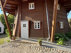 A wooden house with a sloped roof, a white door, and two windows. - fewo1846 - Nordwind - Vacation in a historic windmill with max. 2 persons (Flensburg)
